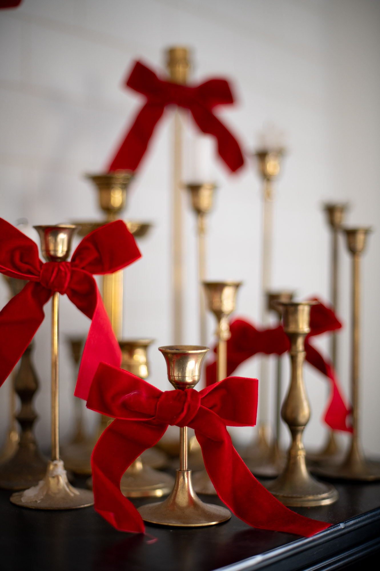 thrifted brass candlestick holders are tied with red velvet ribbon bows