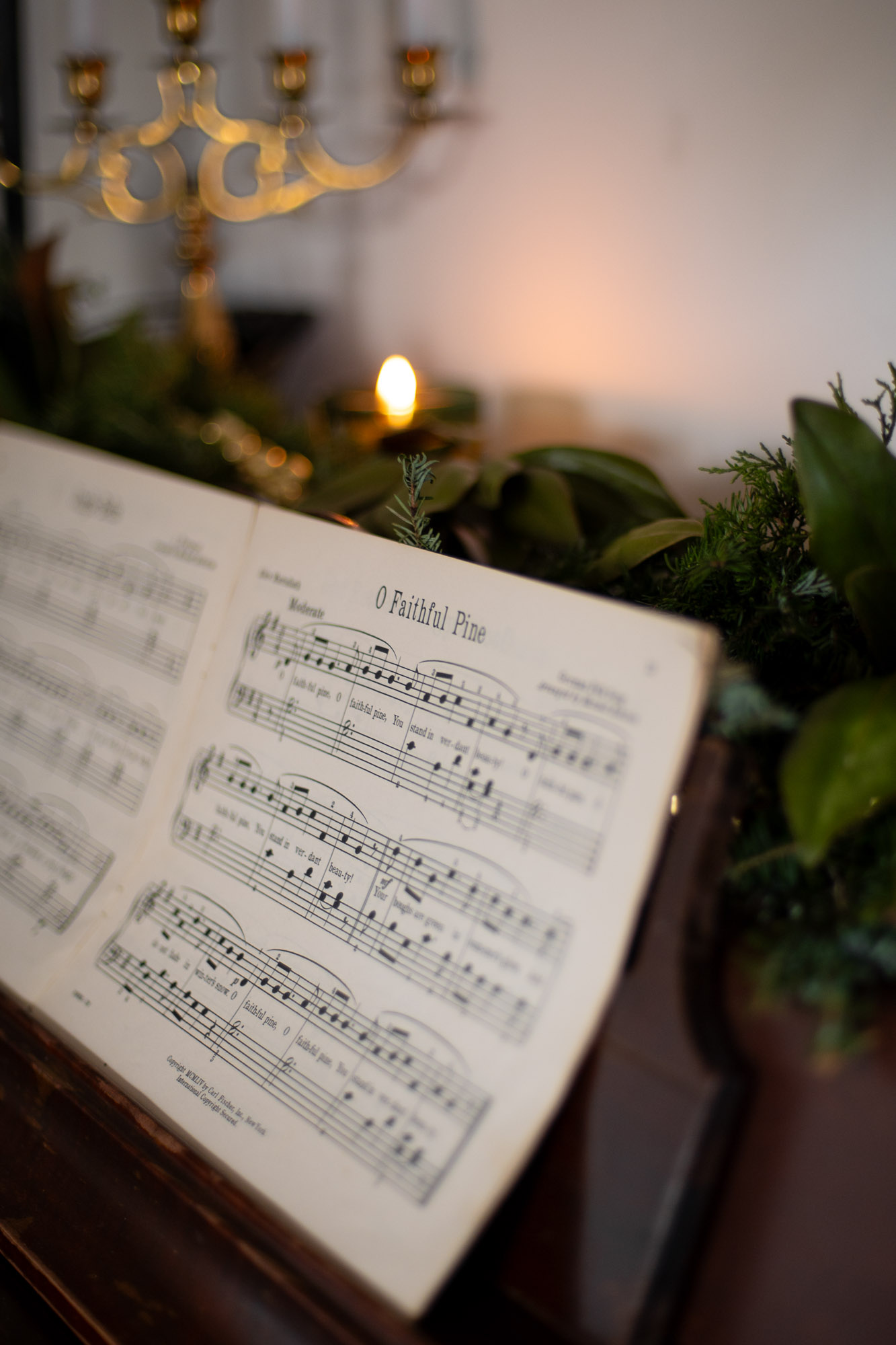 vintage christmas sheet music sits on a piano decorated with fresh evergreen garland