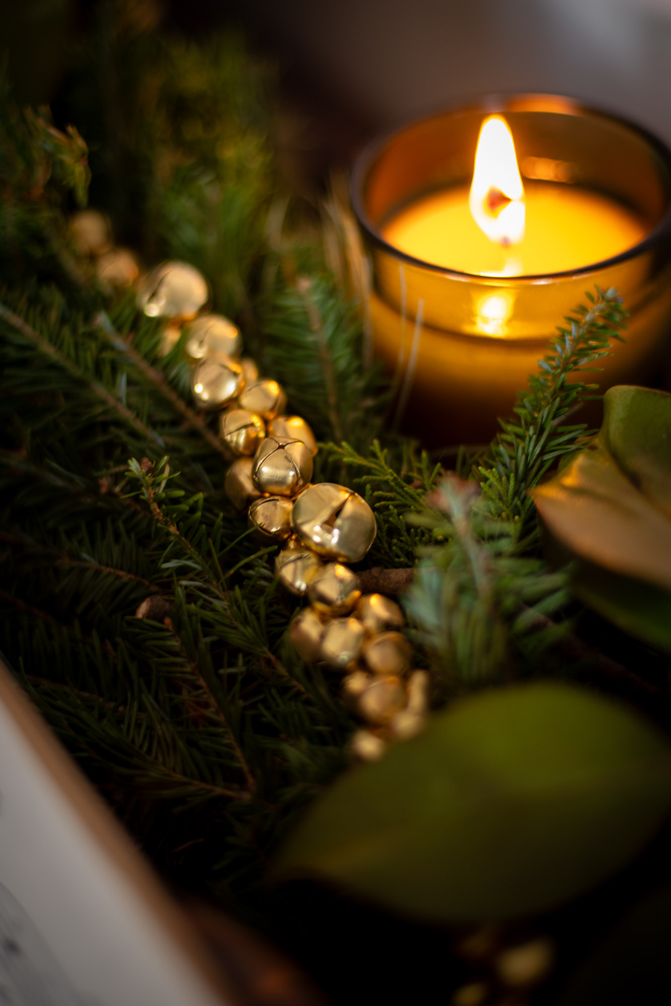 diy garland made from brass jingle bells is woven into fresh evergreen garland on top of a piano.