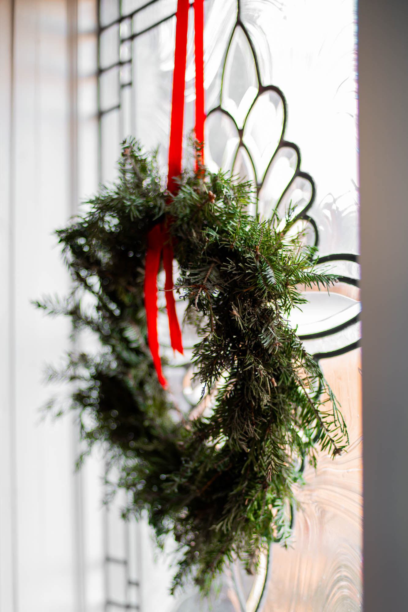 a simple fresh evergreen wreath hangs in a window in a vintage kitchen