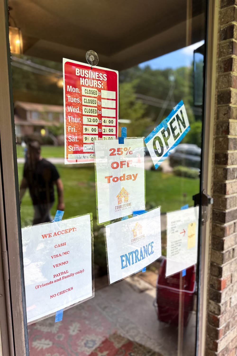 Estate sale entry door with sale hours, discount announcement and types of payment accepted