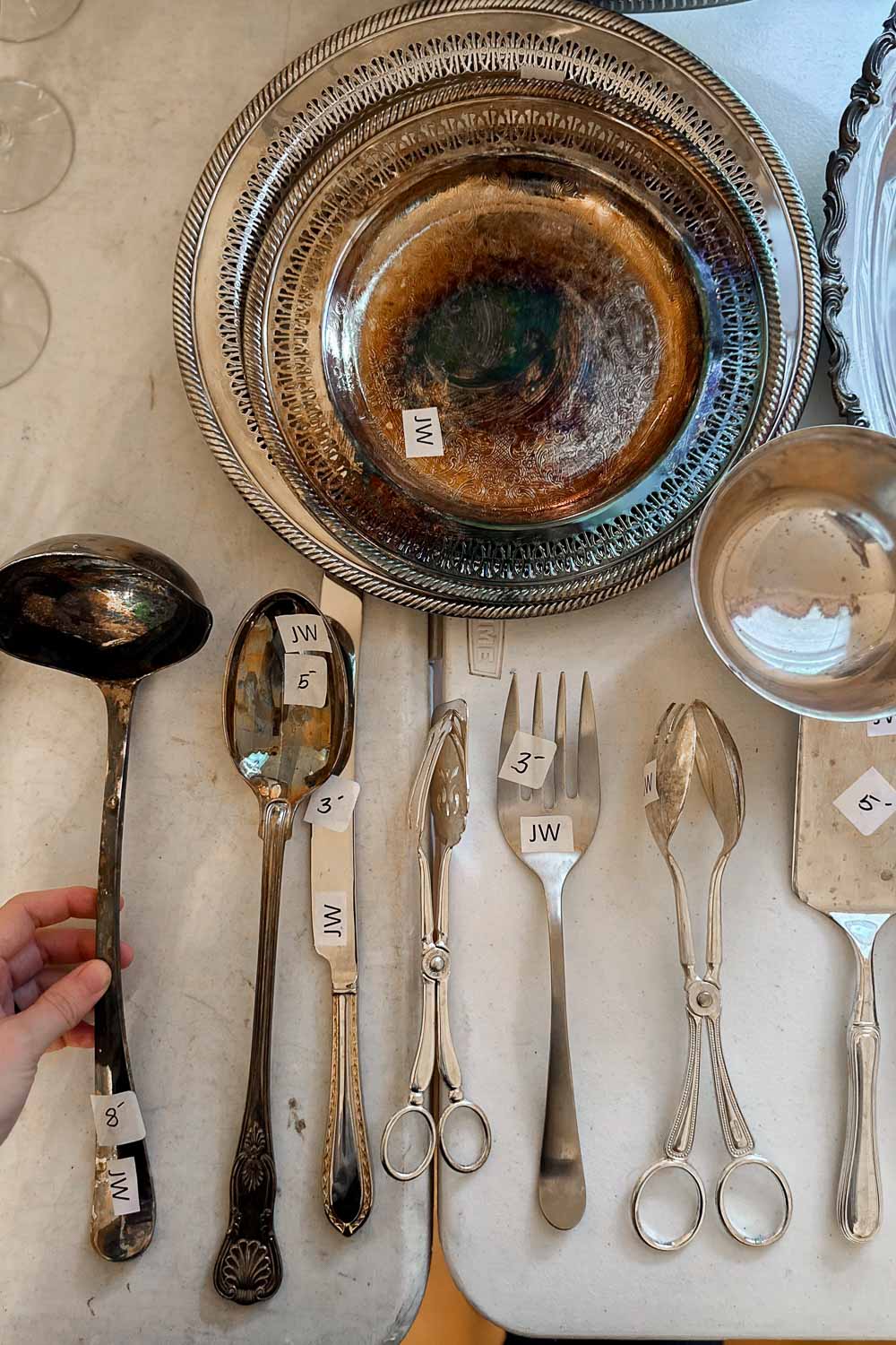 a collection of silver serving ware for sale at an estate sale.