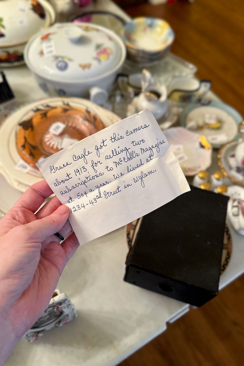Vintage camera on table at estate sale with handwritten note from previous owner