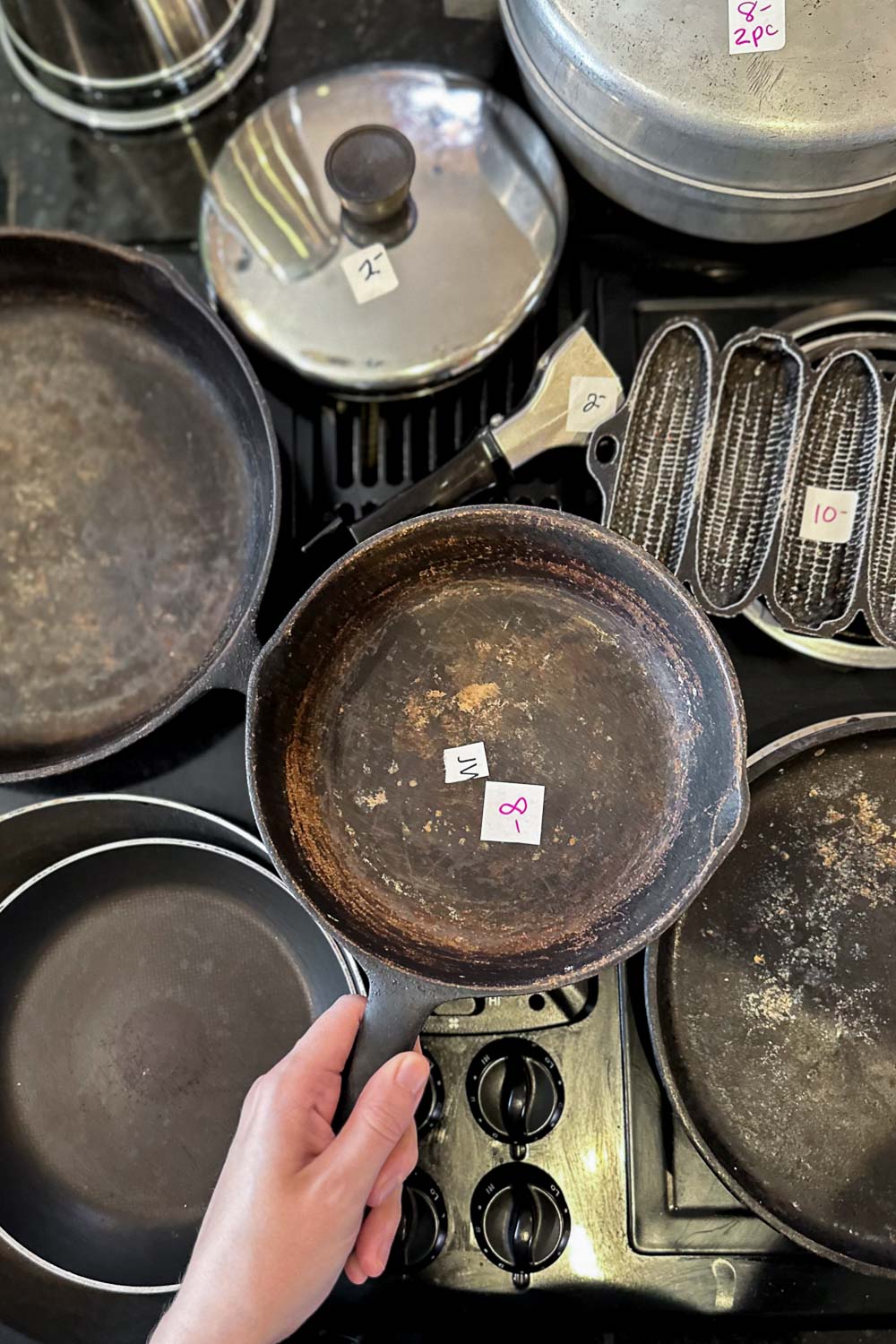 vintage cast iron cookware for sale at an estate sale with a handwritten price tage
