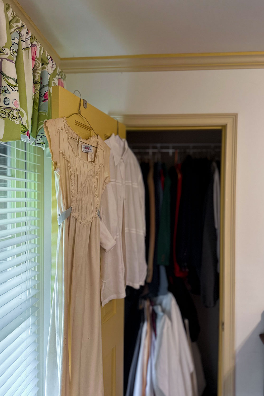 Antique cream nightgown hanging in doorway at estate sale with peek into closet