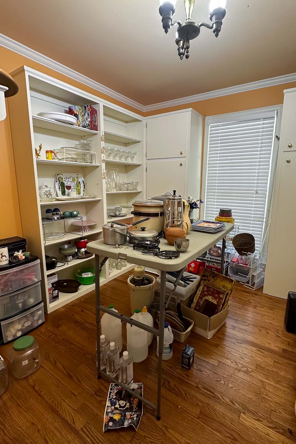 a butler's pantry at an estate sale with kitchenware and candles for sale.