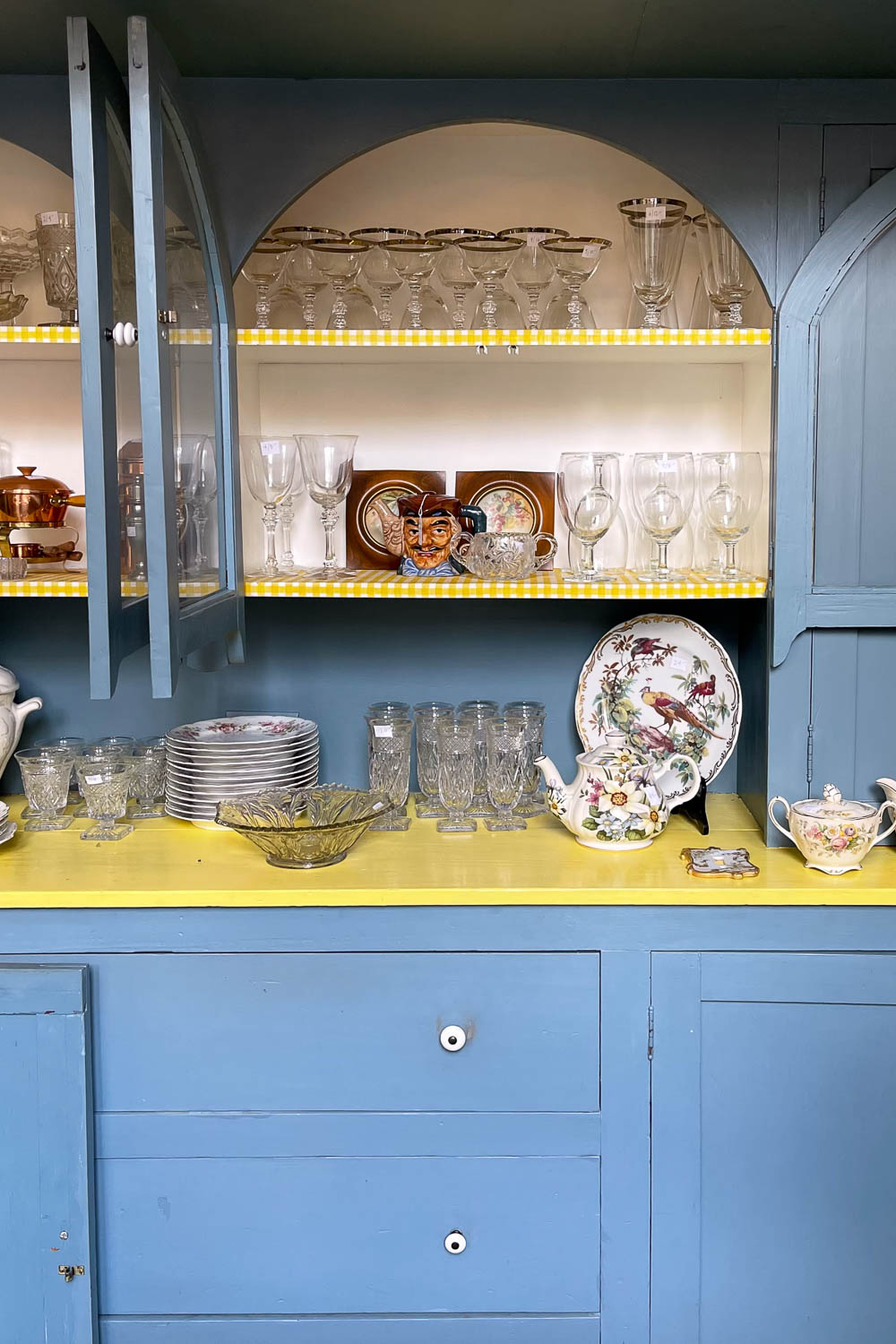 Estate sale kitchen with vintage blue cabinets and retro dishware on display
