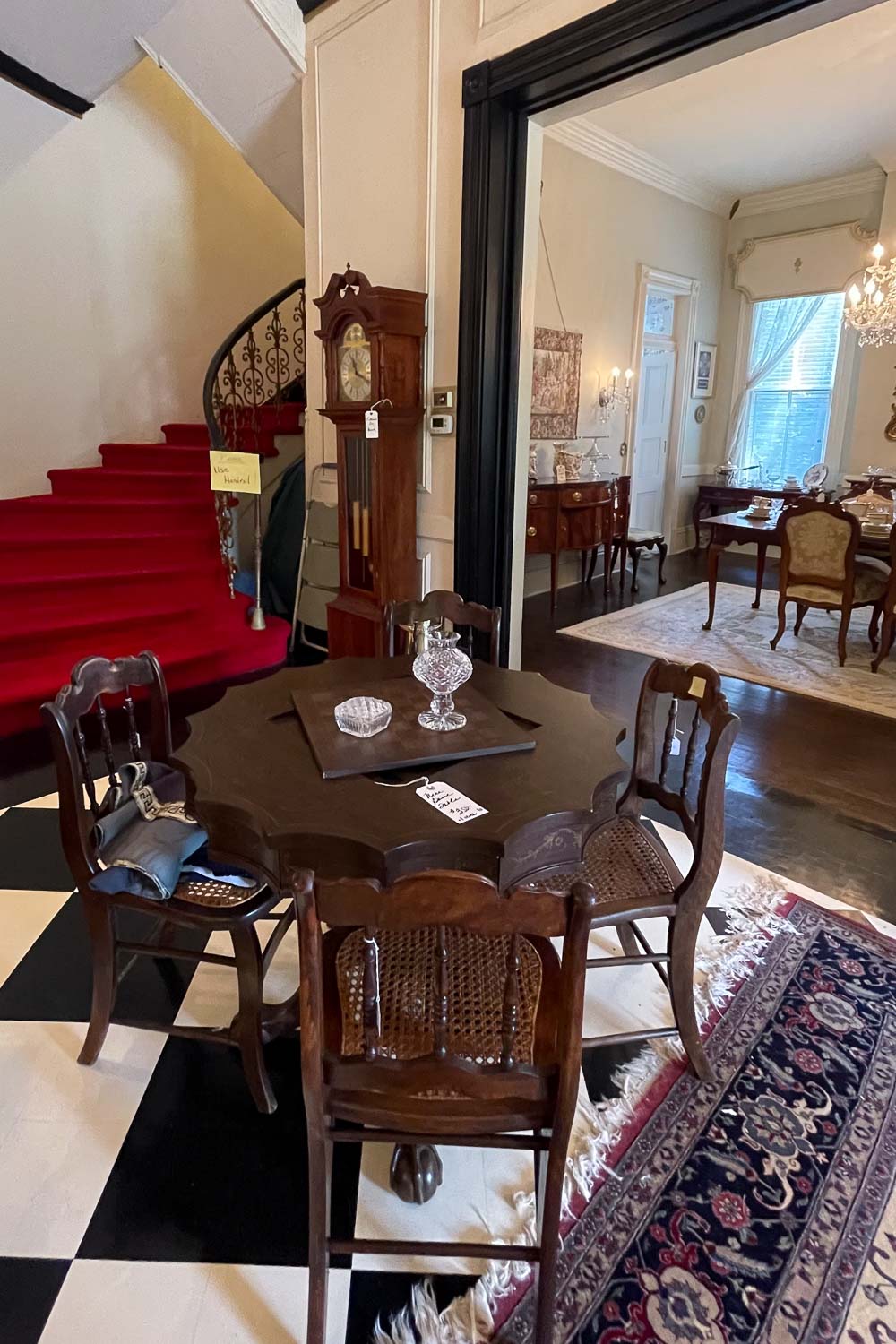 the entry hall of an estate sale in an old manor house showing a variety of antique furniture for sale.