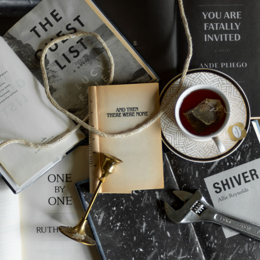 an overhead view of a table showing the title page of agatha christie's book and then there were none surrounded by the best modern closed circle mystery and locked room mystery book along with various murder weapons.
