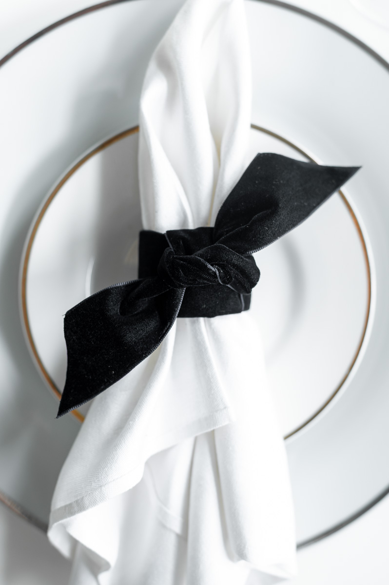 DIY black velvet napkin ring on a moody Halloween-inspired tablescape with dark accents.