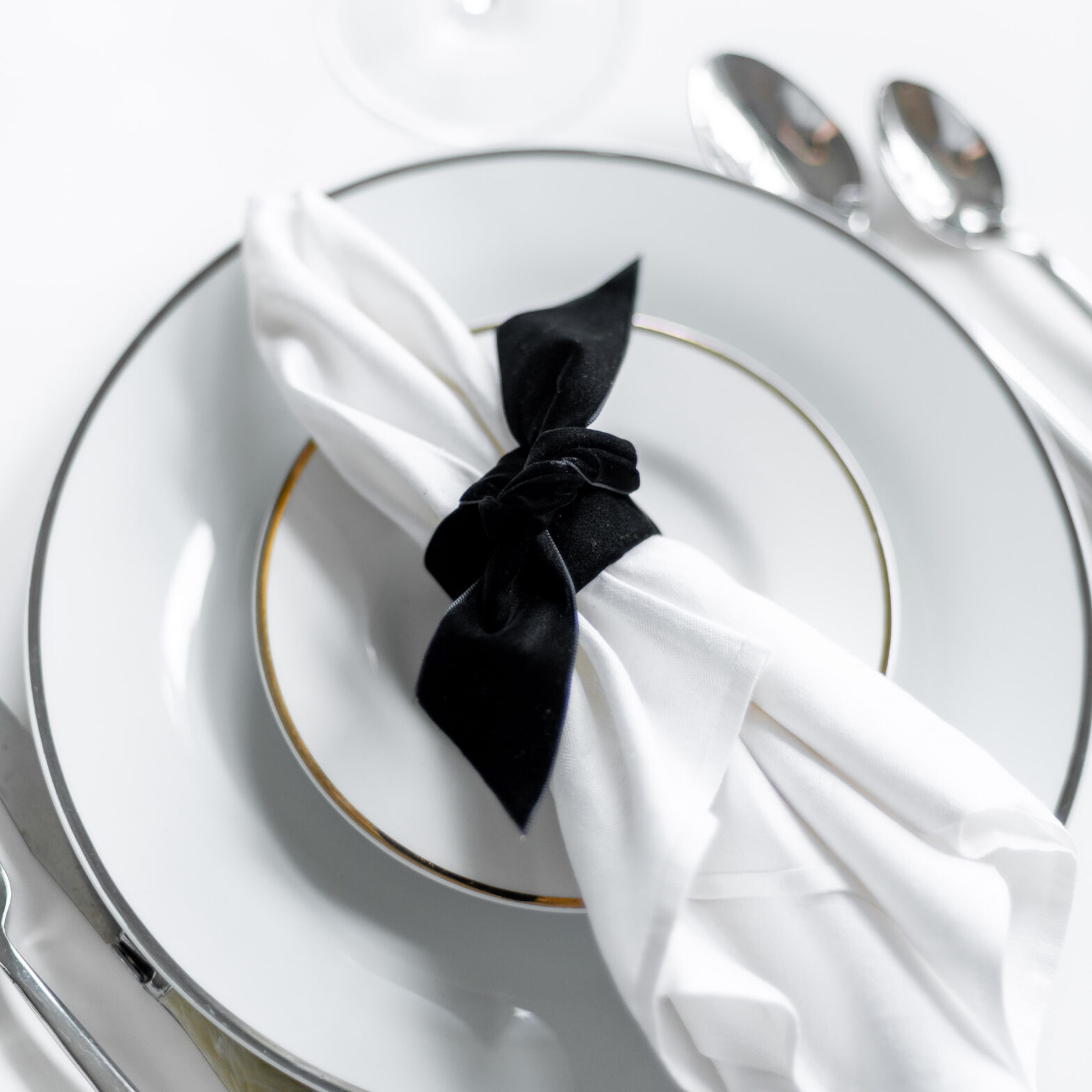 DIY Napkin Ring created from black velvet ribbon holding a white napkin laid on a formal place setting