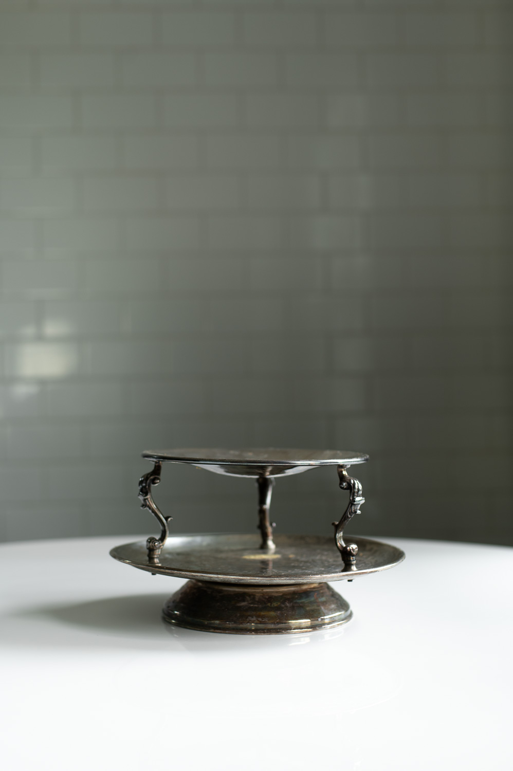 a thrifted two tier silver tray sits on a white table.
