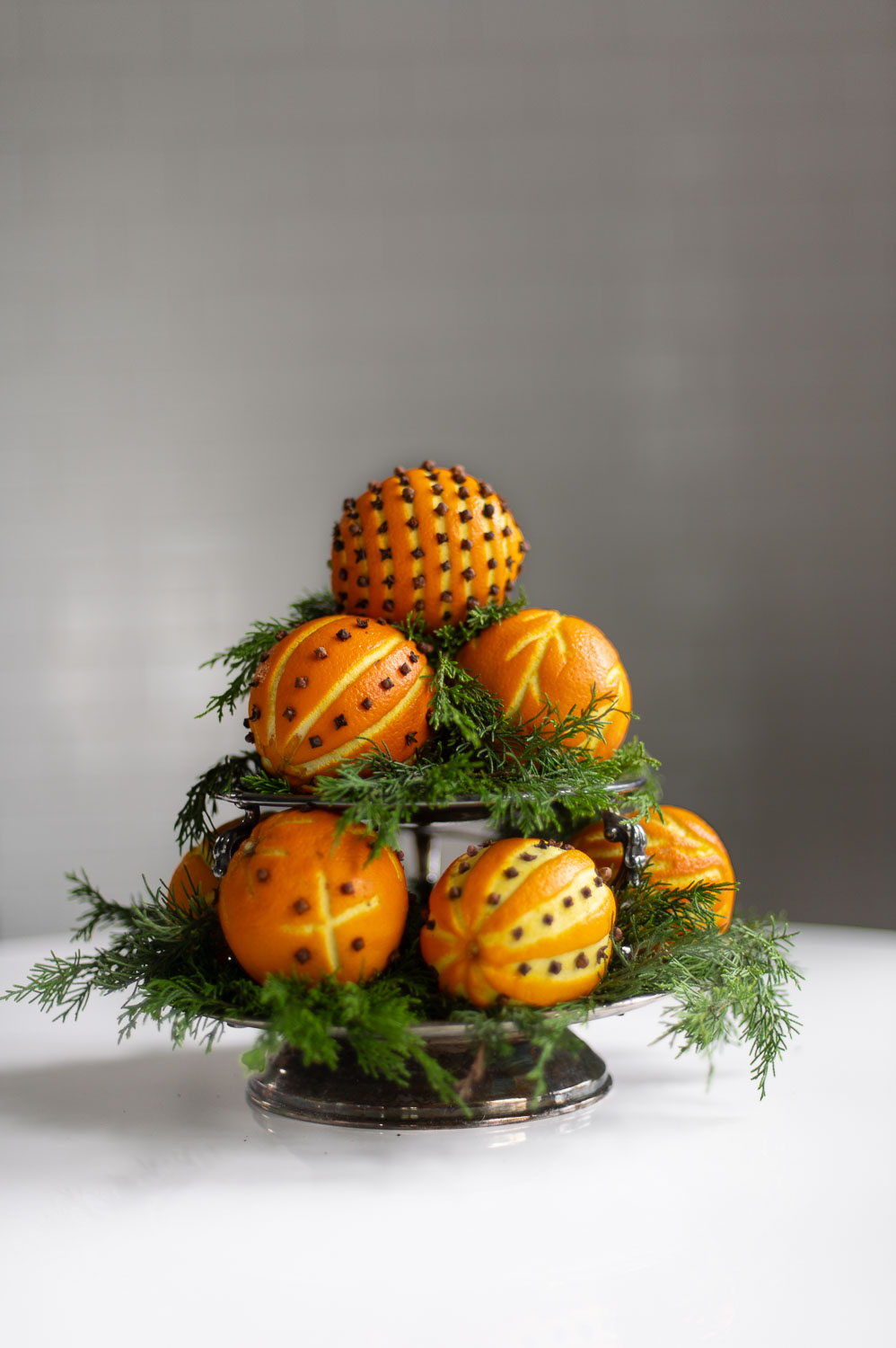 a side view of an orange pomander tower made from orange clove pomanders and fresh greenery for natural christmas decor.