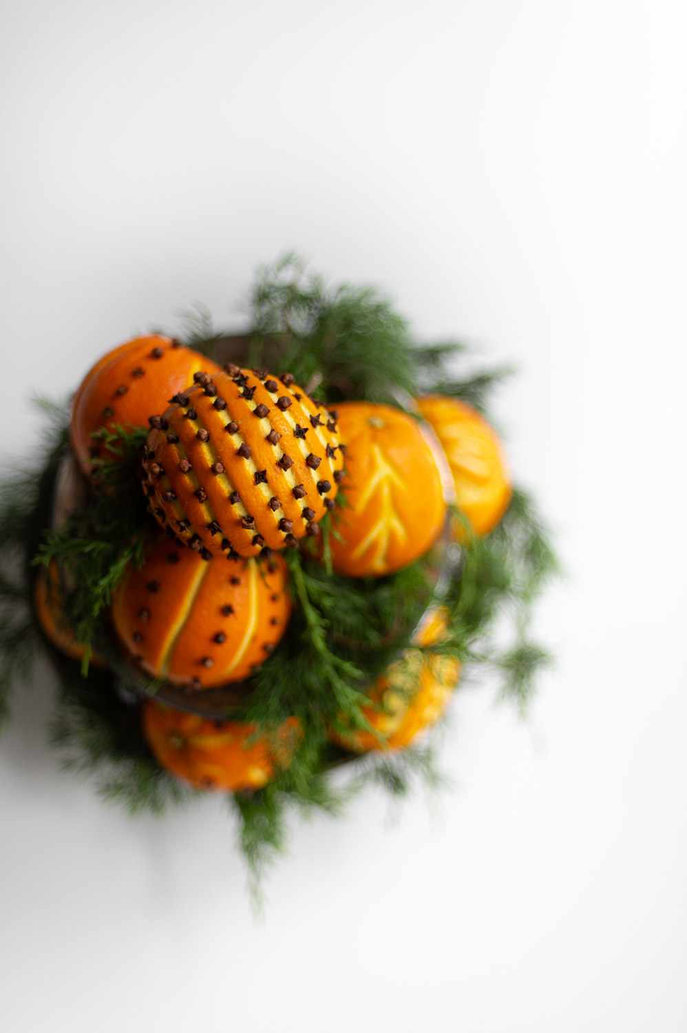 a top view of an orange pomander stack made from orange clove pomanders and fresh greenery for natural christmas decor.