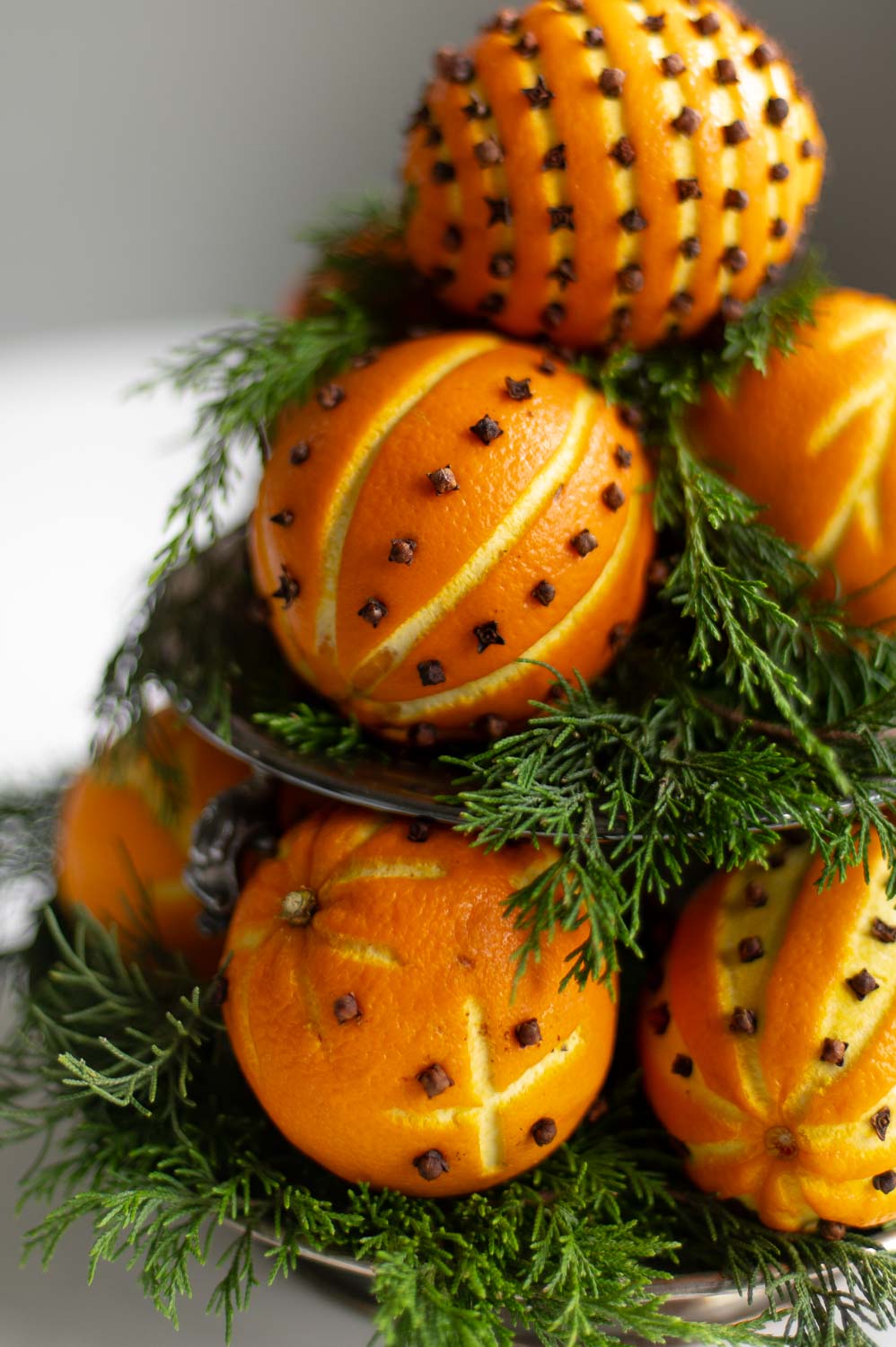 a closeup view of an orange pomander ball centerpiece made from orange clove pomanders and fresh greenery for natural christmas decor.