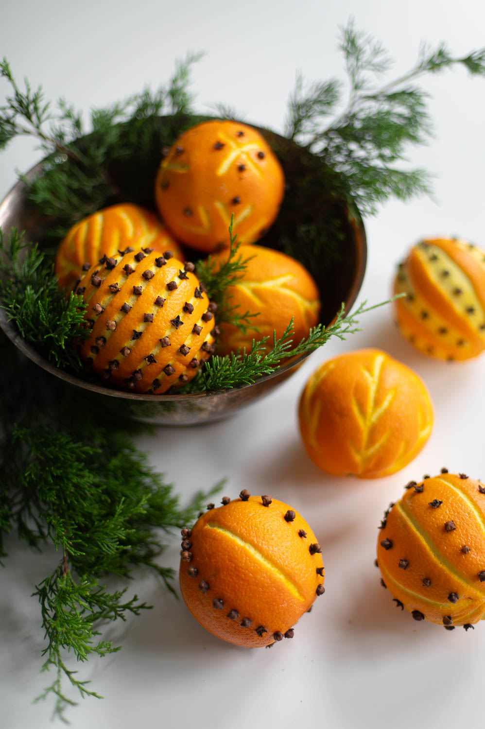 a thrifted silver bowl filled with fresh Christmas greenery and decorative orange clove pomander balls