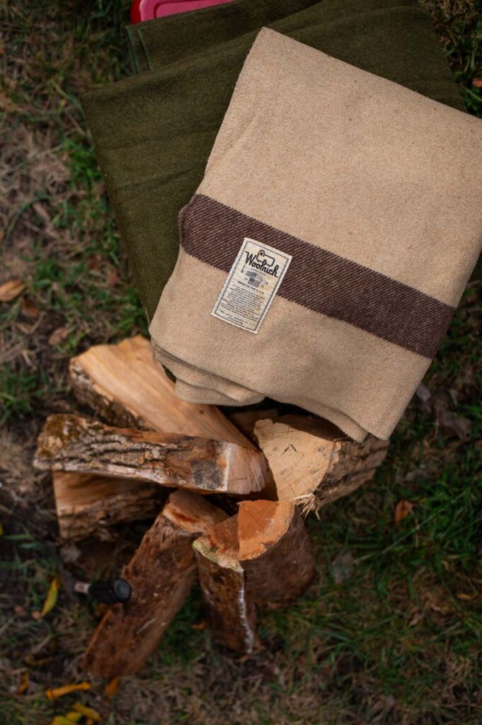 Stacked firewood and vintage wool blankets as rustic decor for a fall bonfire night party.