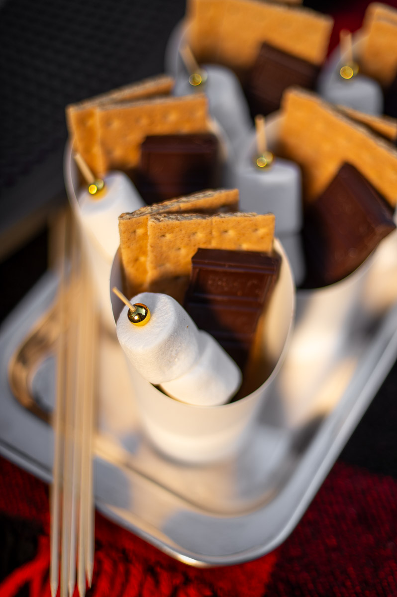 Individual charcuterie s’mores cups filled with marshmallows, chocolate, and graham crackers for a fall bonfire party.