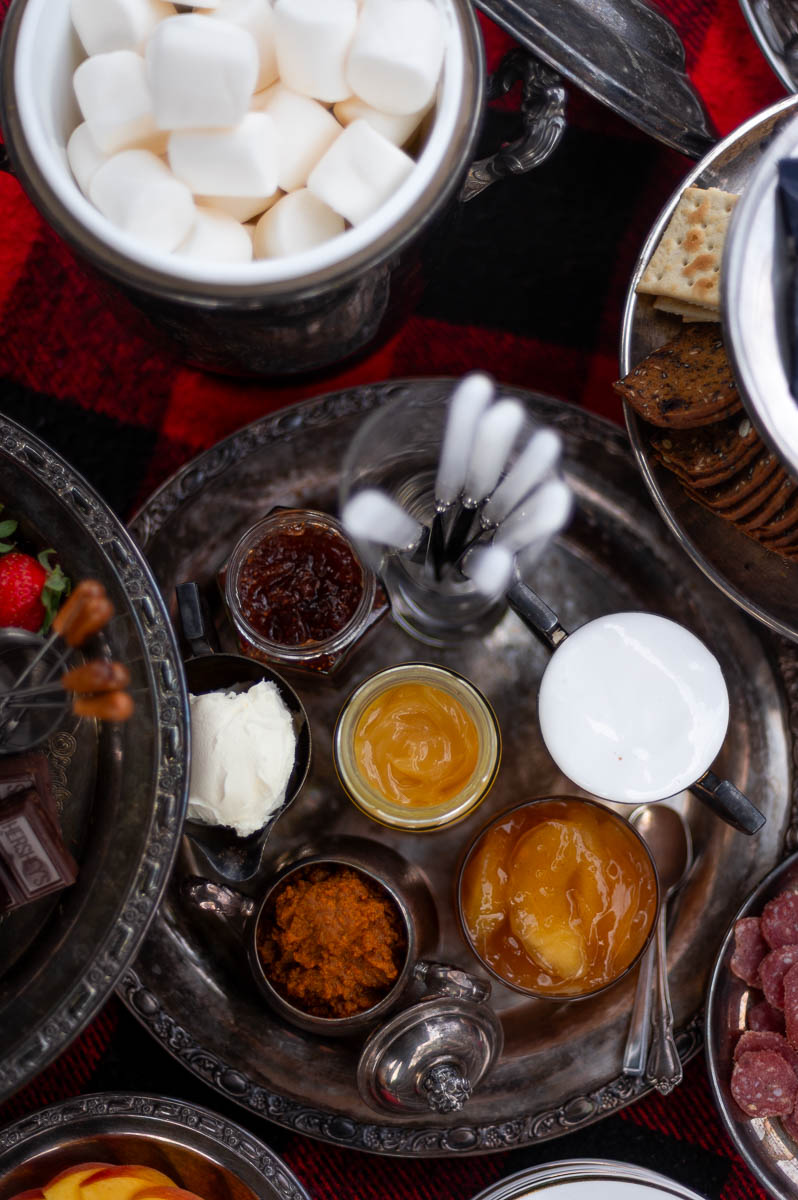 Vintage-inspired s’mores station with jams, spreads, and marshmallows styled for a backyard bonfire party.
