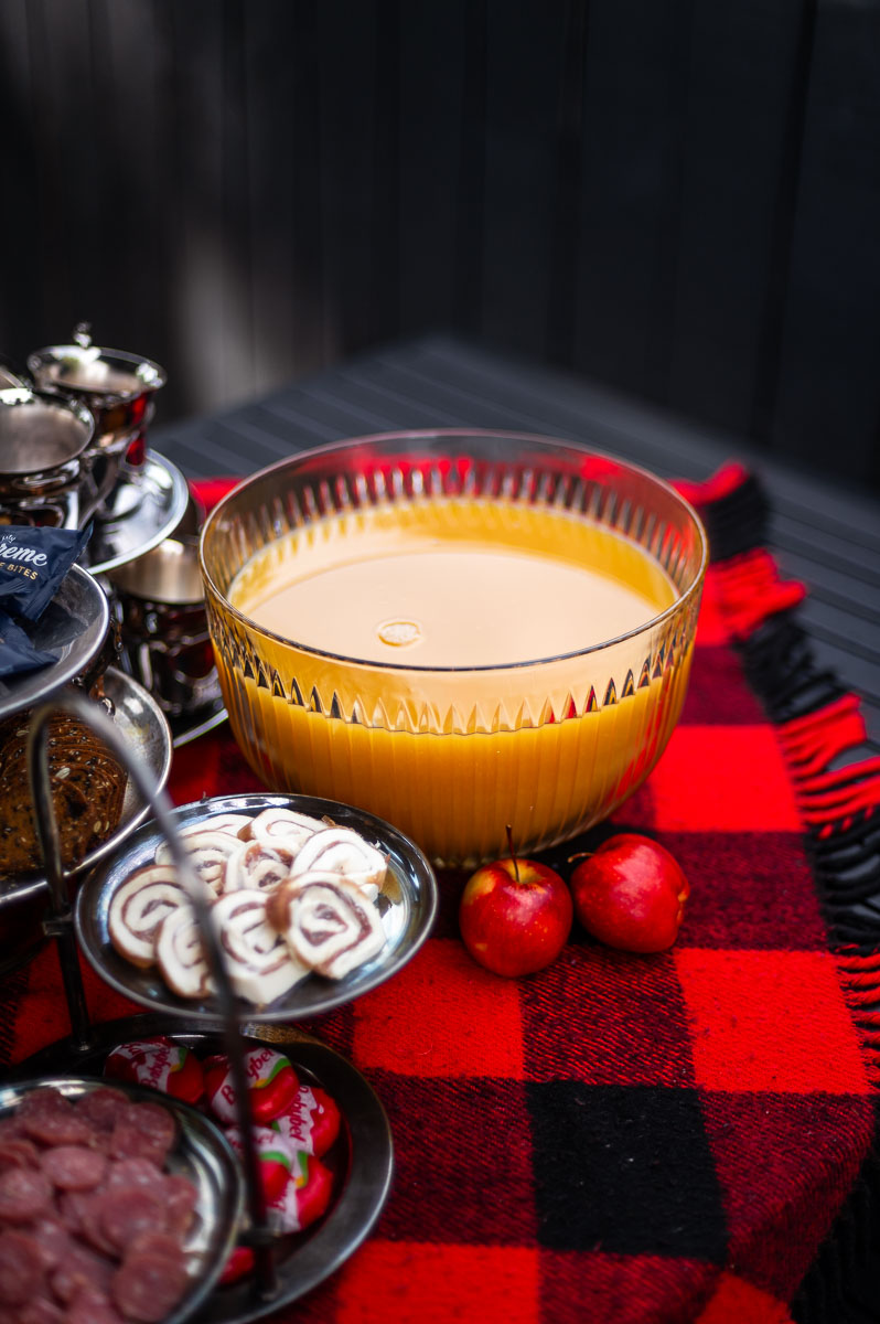 Simple harvest punch display featuring a vintage punch bowl of apple cider punch non alcoholic and silver cups for a cozy fall party.