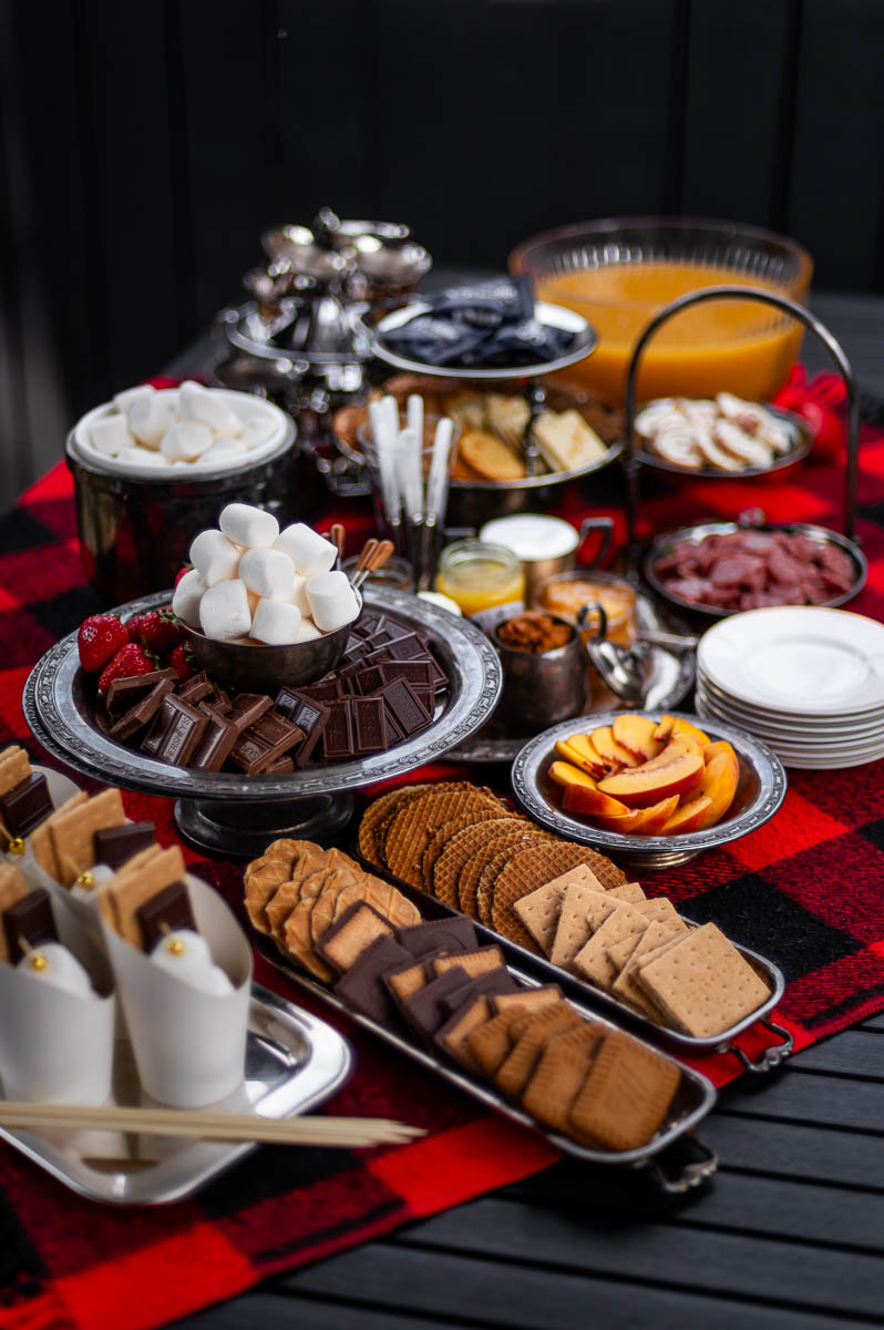 Large s’mores charcuterie board with gourmet toppings set out for a backyard s’mores party bonfire.