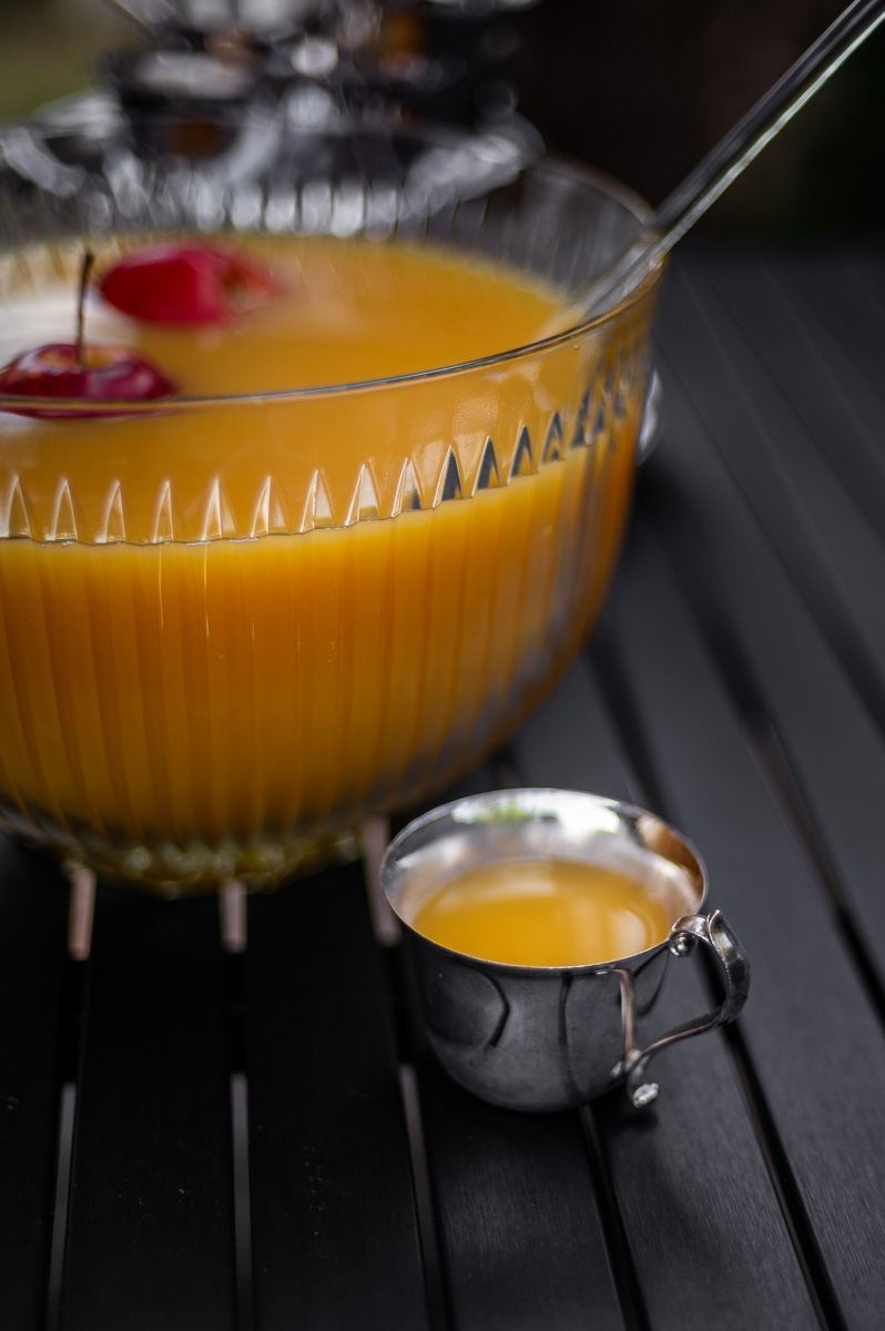 Fall party punch in a vintage glass bowl with floating apples and silver punch cups, ideal for autumn punch recipes non alcoholic or a harvest punch centerpiece.