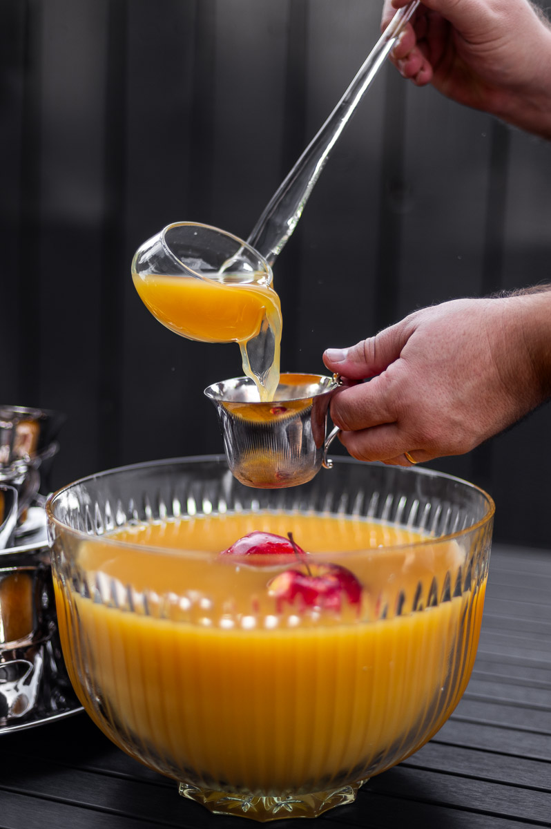 Fall party punch in a vintage glass bowl with floating apples and silver punch cups, ideal for autumn punch recipes non alcoholic or a harvest punch centerpiece.