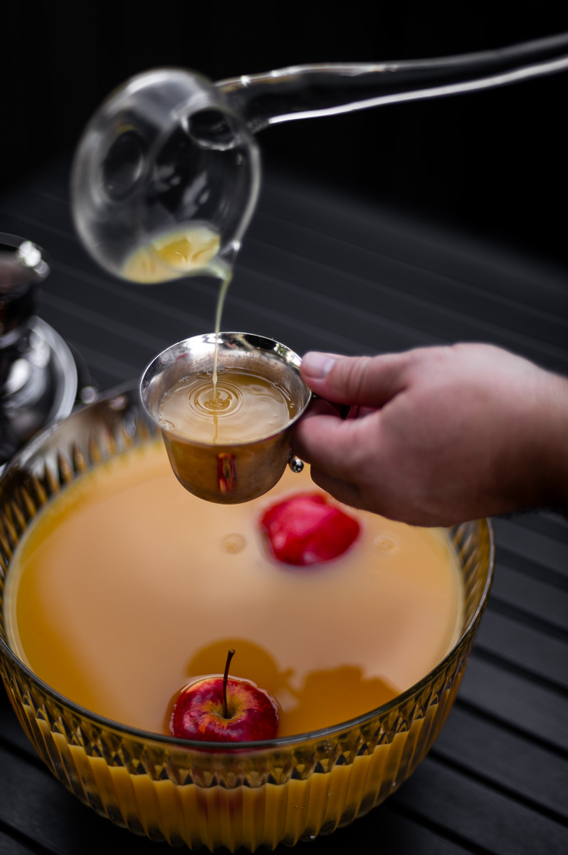 Fall party punch in a vintage glass bowl with floating apples and silver punch cups, ideal for autumn punch recipes non alcoholic or a harvest punch centerpiece.