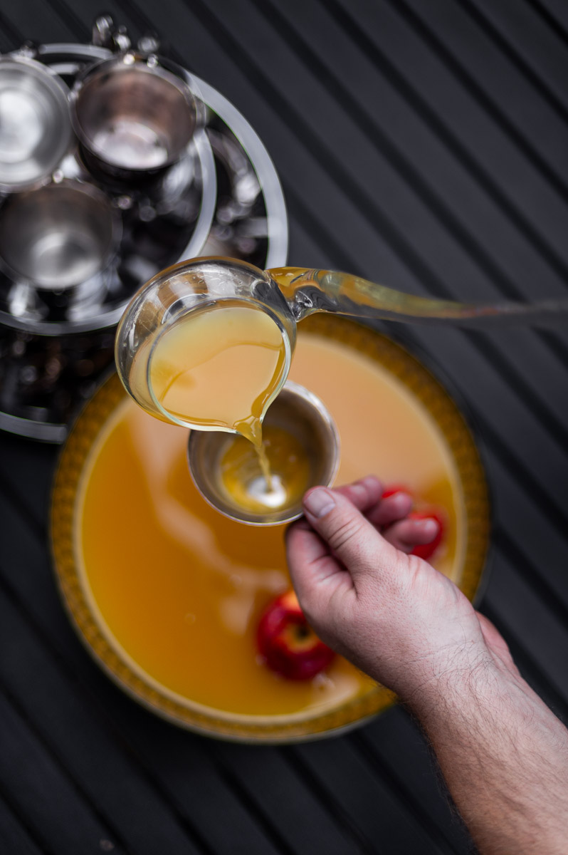 Vintage glass punch bowl filled with apple cider punch non alcoholic, garnished with whole apples and vintage silver punch cups, perfect for a Thanksgiving punch non alcoholic recipe.