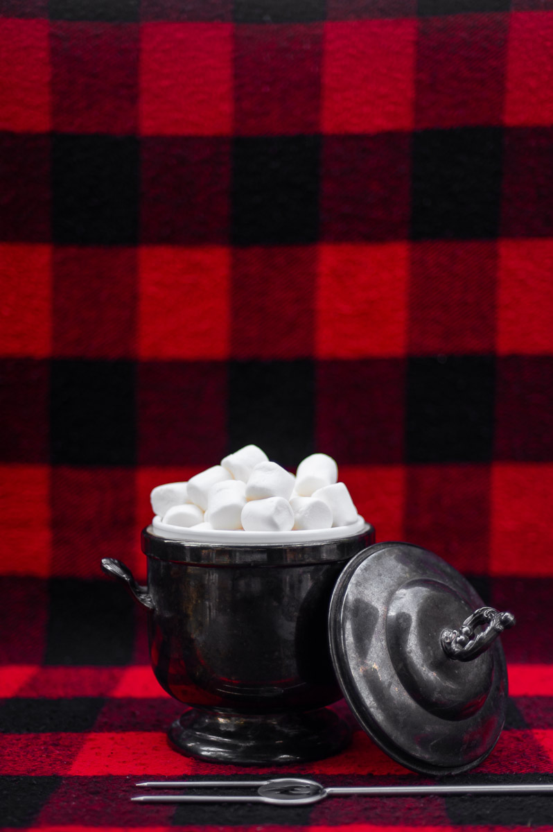 A thrifted vintage silver champagne bucket styled with marshmallows and a roasting stick for an elegant fall campfire party.