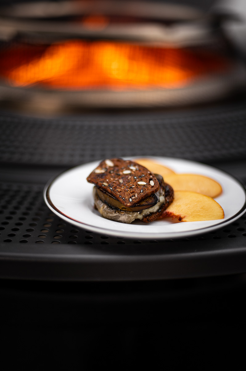 Close-up of roasted peach roasted brie with fig jam on cranberry cracker – unique savory s’mores charcuterie combo.