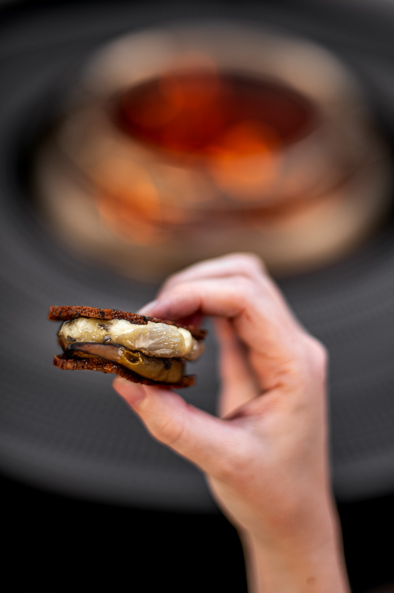Woman holding a savory smore with roast peach, brie honey and fig jam at a backyard bonfire party