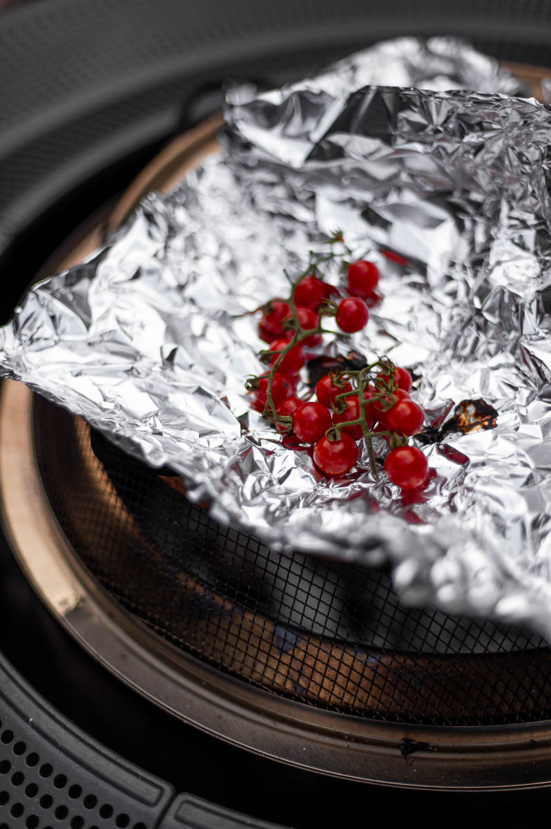 Homegrown tomatoes roasting over a backyard campfire during a fall bonfire party.