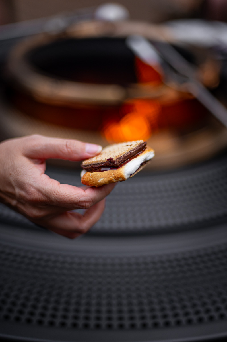 woman holding a gourmet s'more in front of a solo stove fire pit at a bonfire party
