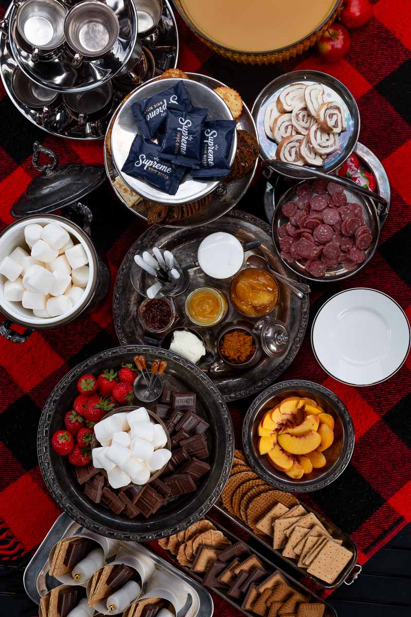 Overhead shot of elegant s’mores charcuterie board on plaid blanket – vintage style grazing table with marshmallows, fruit, cookies, and chocolate.