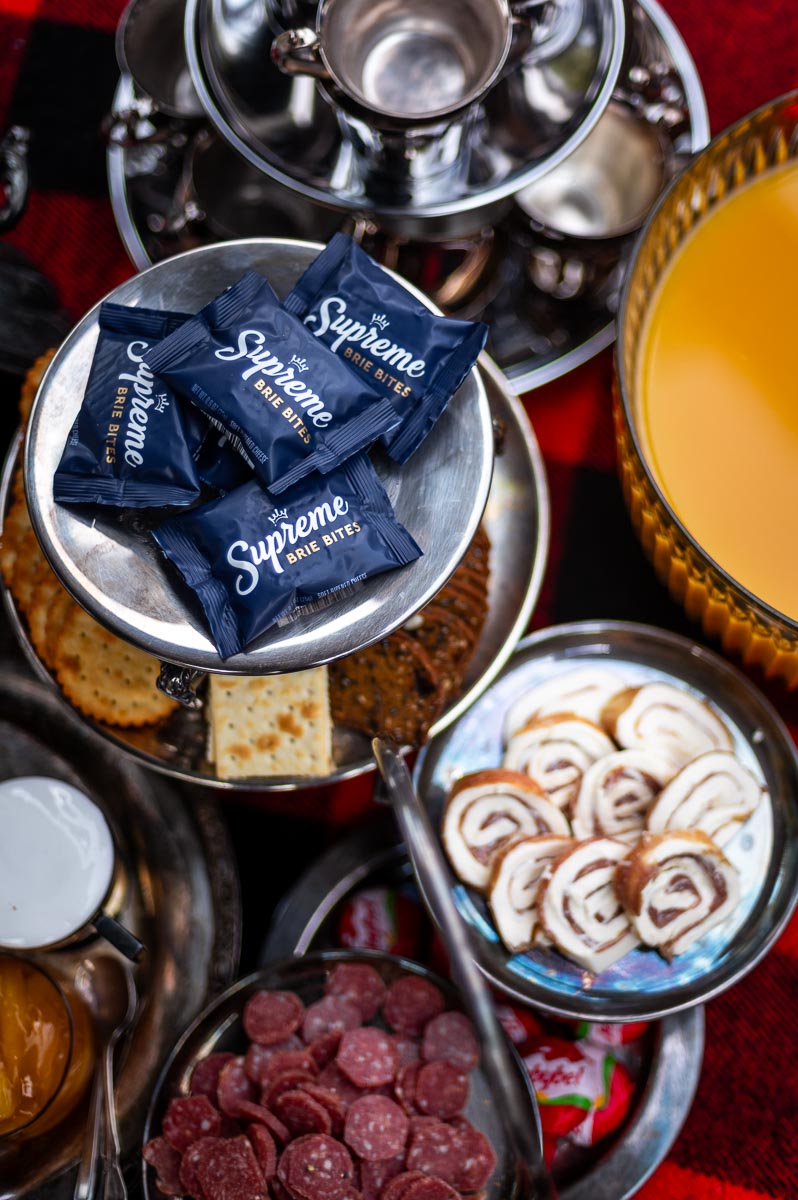Prosciutto pinwheels, brie bites, and mascarpone on vintage platter – elegant savory options for s’mores grazing table.