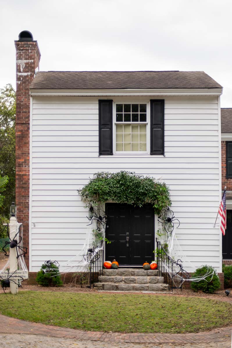 spooky front porch decor for Halloween on a white historic home in Huntsville alabama with DIY spiderwebs and large spiders