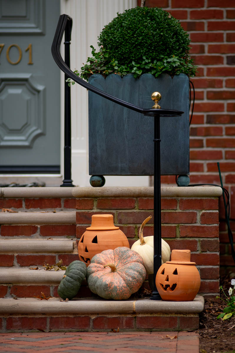 terracotta pumpkins sitting next muted fall pumpkins in a fall front porch display.