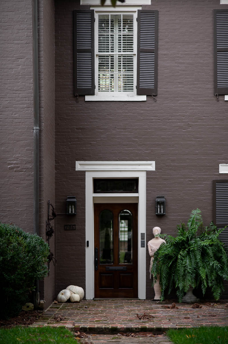 gauze wrapped mummy next to a giant fern in front of historic house to create elegant spooky fall front porch decor