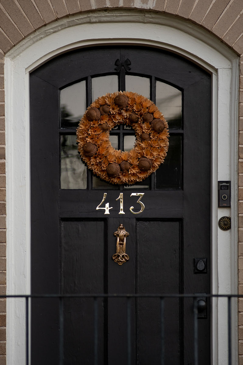 natural wood chip fall wreath for front door with acorns in front of a black door on a historic house