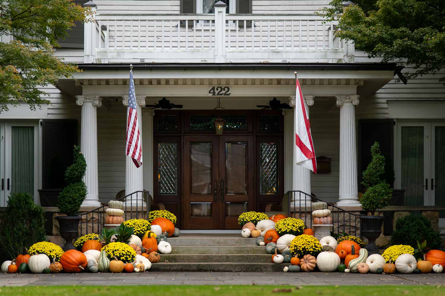 decorating ideas for the front porch from the historic Twickenham neighborhood of Huntsville Alabama showcasing a cascade of fall pumpkins and mums in front of a historic home.
