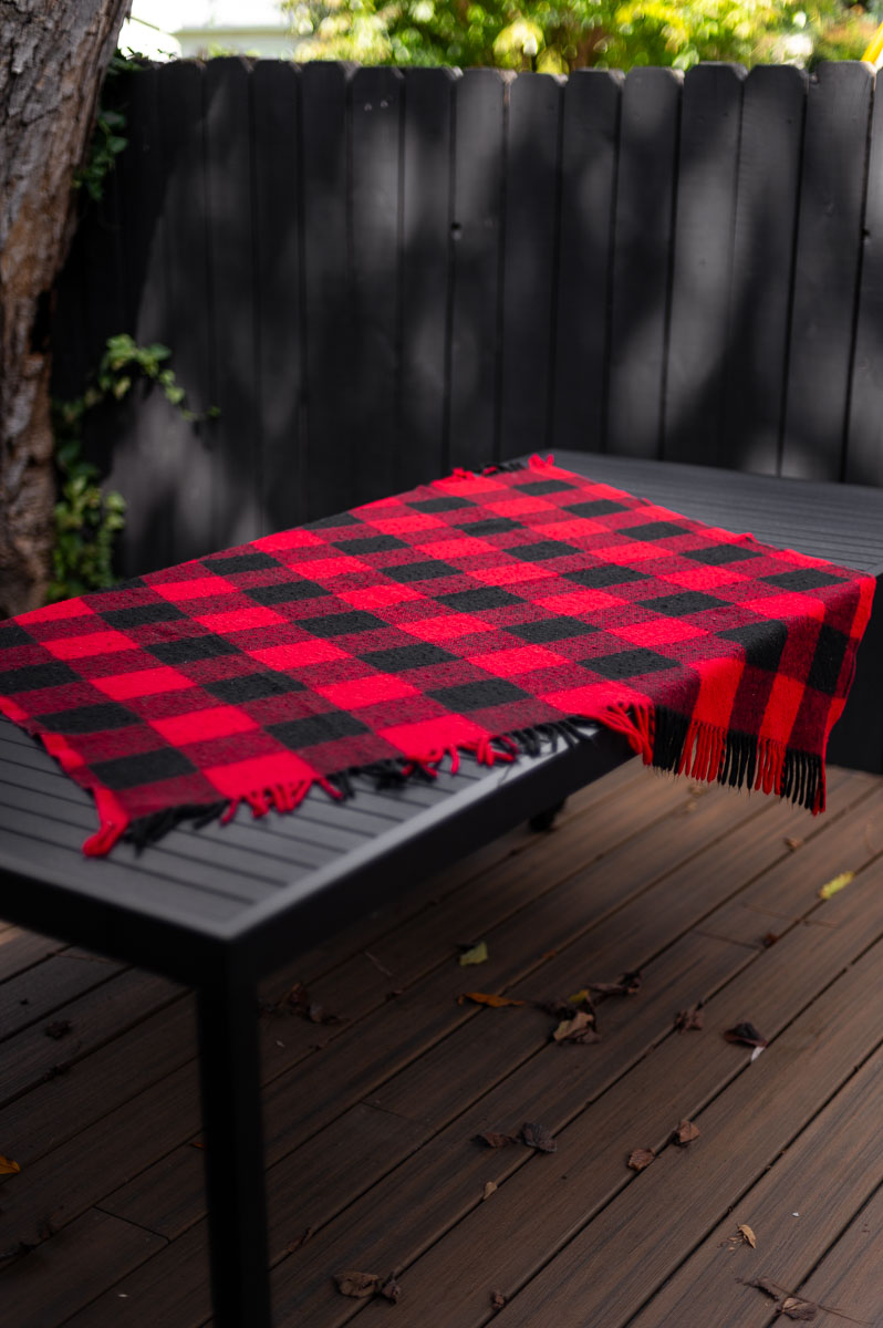 Close-up of plaid blanket layered over outdoor table – rustic base for s’mores grazing table setup.