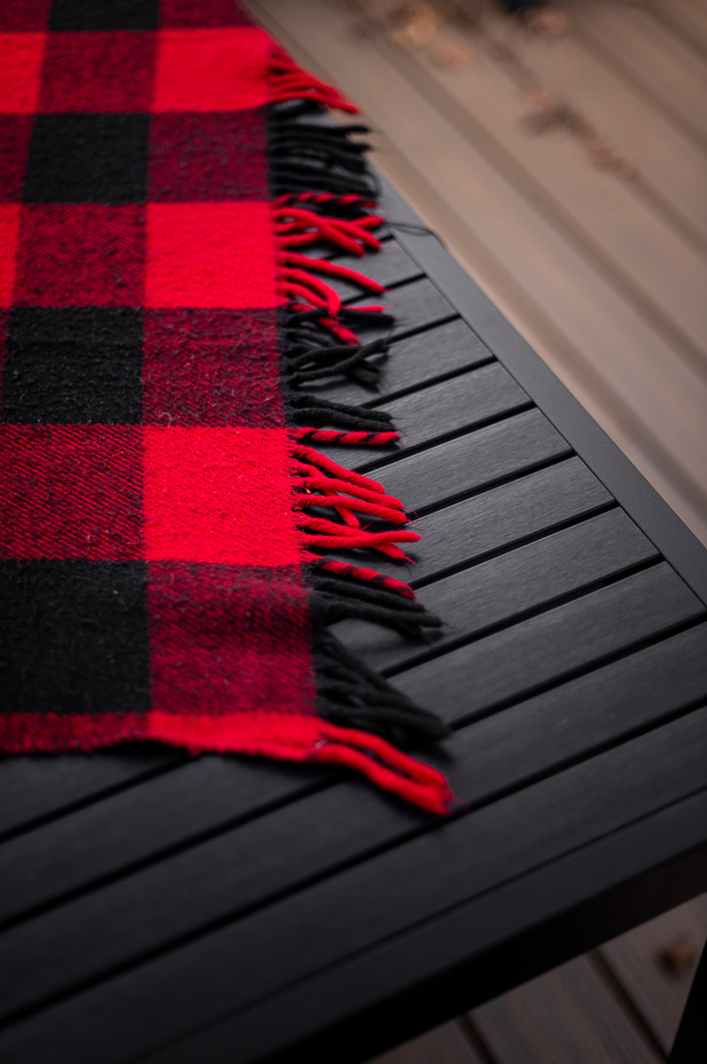 Close-up of plaid blanket layered over outdoor table – rustic base for s’mores grazing table setup.