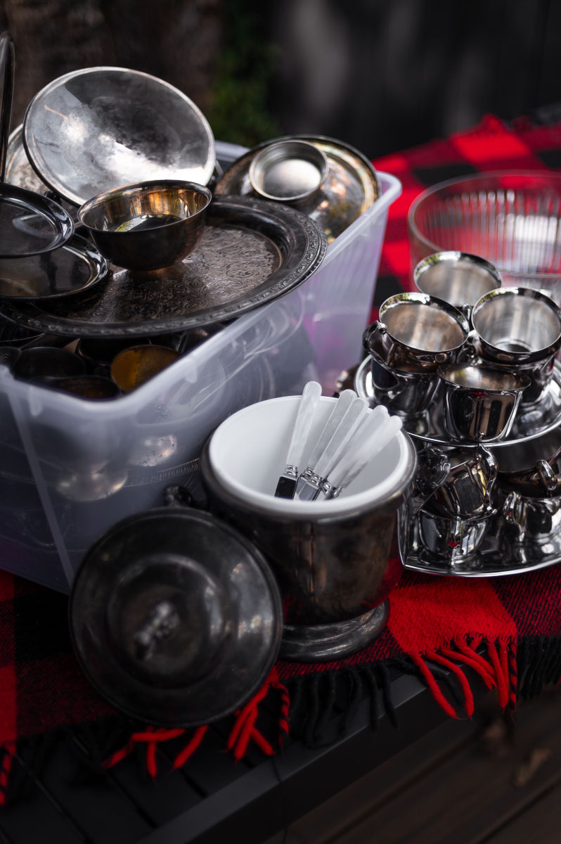 Vintage silver serving platters and bowls on picnic table – preparing the base for a s’mores charcuterie board.