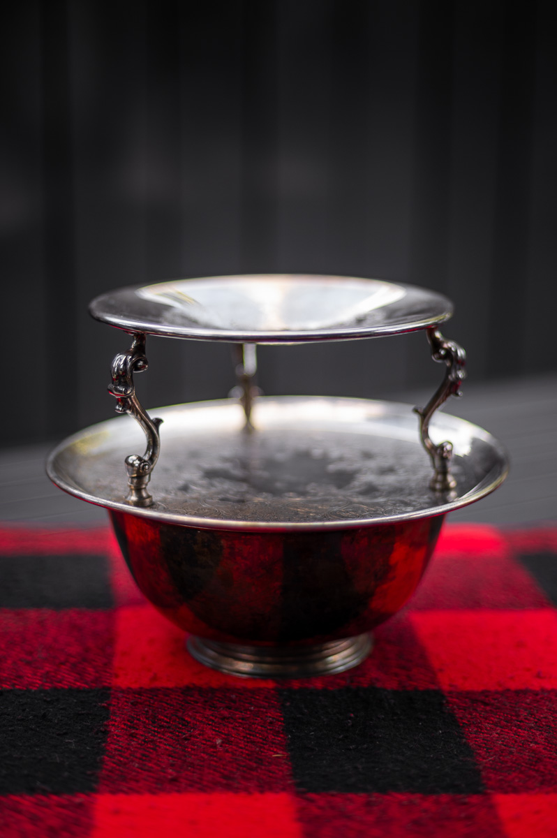 Vintage silver serving platters and bowls on picnic table – preparing the base for a s’mores charcuterie board.