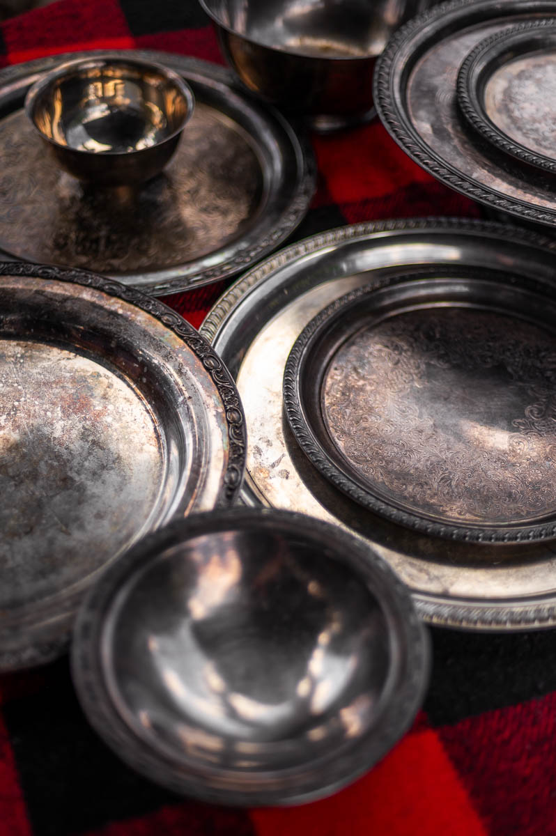 Silver serving bowls and vintage dishes arranged on table – supplies needed for building a s’mores bar.