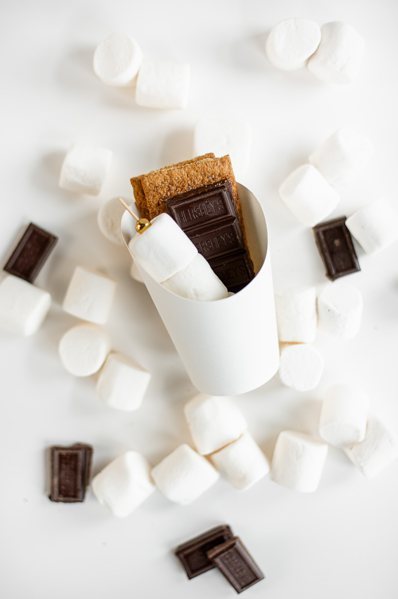 Individual diy s’mores kit with layered graham crackers, chocolate, and marshmallow skewers for summer entertaining.