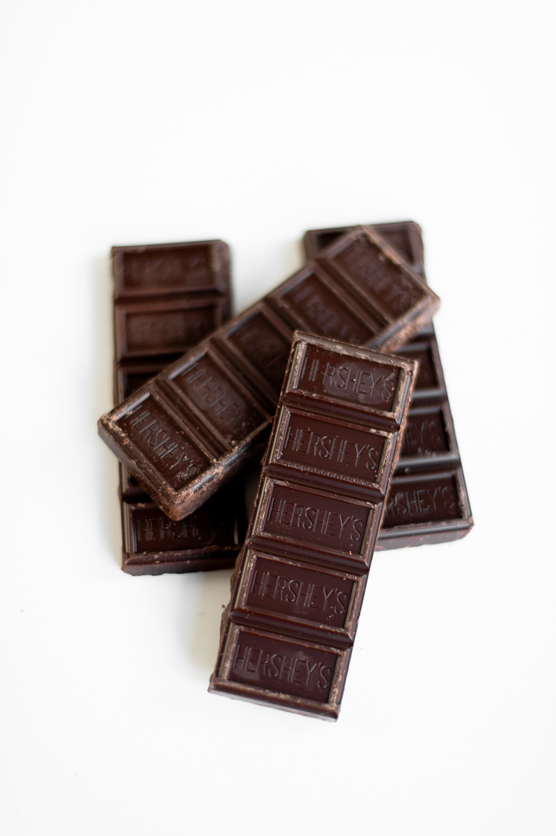 Pile of chocolate bar strips ready to add to s’mores charcuterie cups with graham crackers and marshmallows.