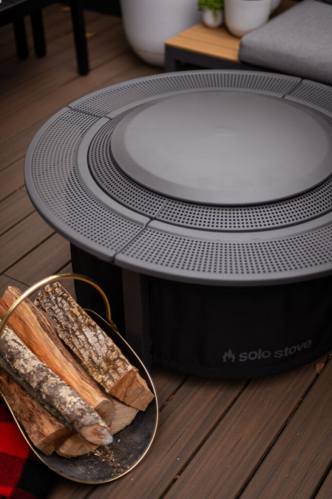 Solo Stove surround surface lid rests on top of a bonfire fire pit on a trex composite deck.