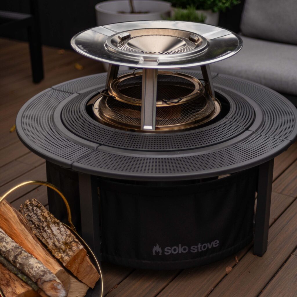 smokeless solo stove bonfire fire pit shown set up on a deck with the solo stove shields spark arrestor, solo stove surround and solo stove heat deflector for a detailed review